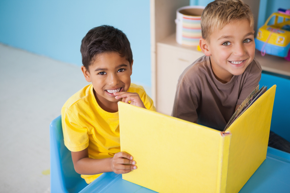 Cute little boys reading at desk in classroom at the nursery school